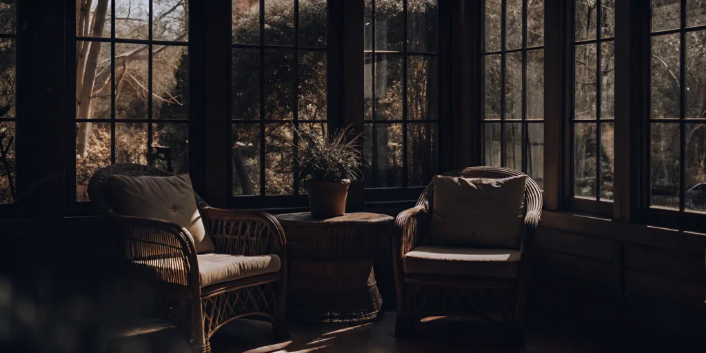 Bright 2nd-floor sunroom with wicker furniture overlooking a garden.